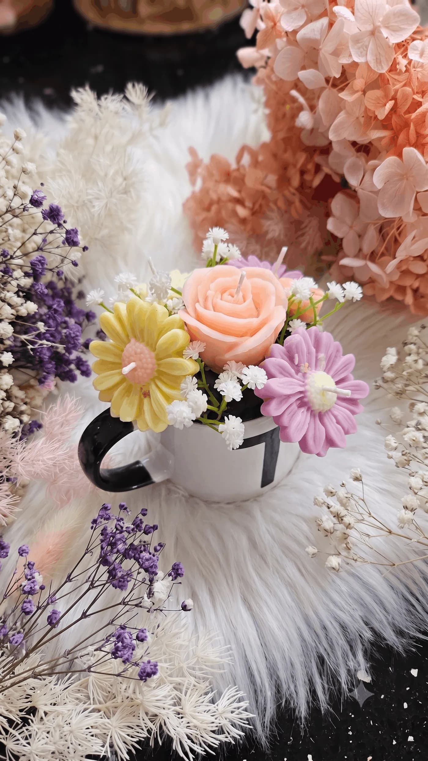 Rose and daisy candle arrangement in a black-and-white mug