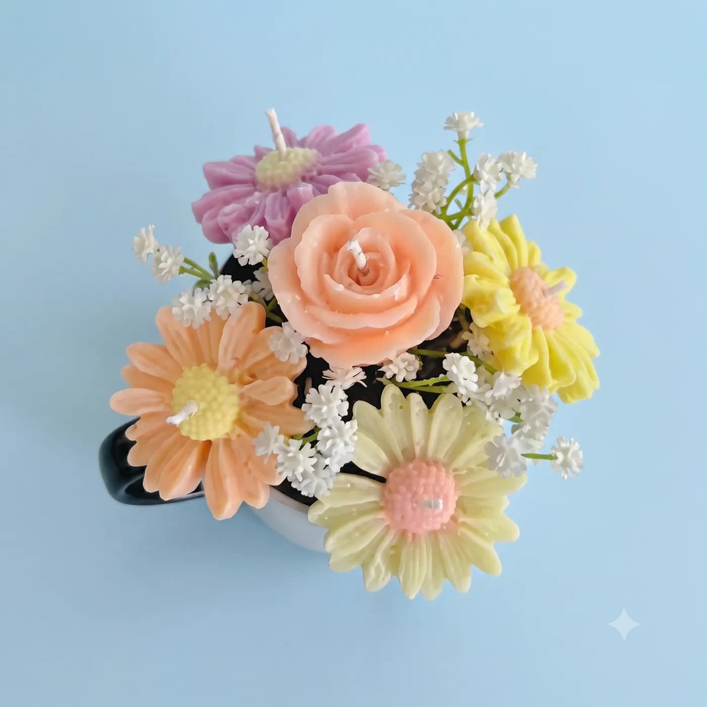 Pastel rose and daisy candle bouquet on a blue background