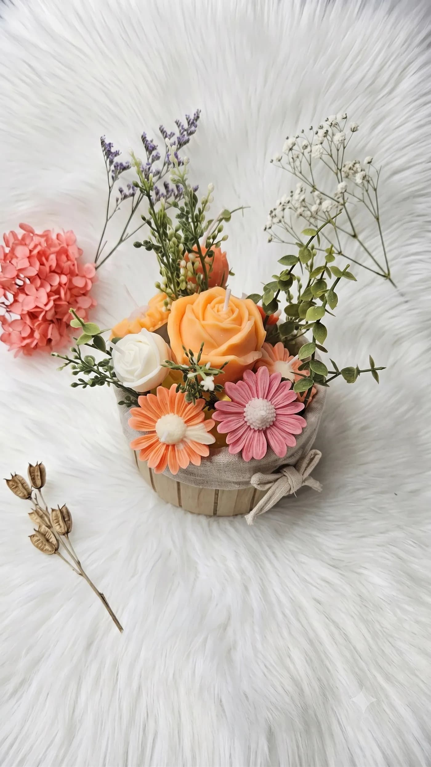 Pastel rose and daisy candle arrangement in a rustic basket